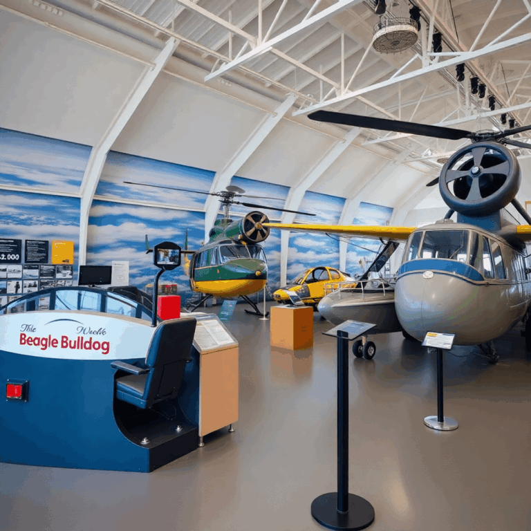 Interior of an aviation museum showcasing a Beagle Bulldog flight simulator, vintage Skeeter helicopter, Saunders Roe Princess flying boat, and int...
