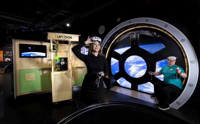 Dr Lynn Verschuren of UofG's Museums in the Metaverse team and Derek Shirlaw of the Glasgow Science Centre try out the [un]box VR kiosk at the Glas...