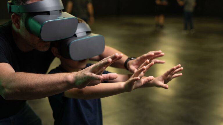 A parent and child in a free-roam VR arena reach out with bare hands and no controllers, wearing generic headsets