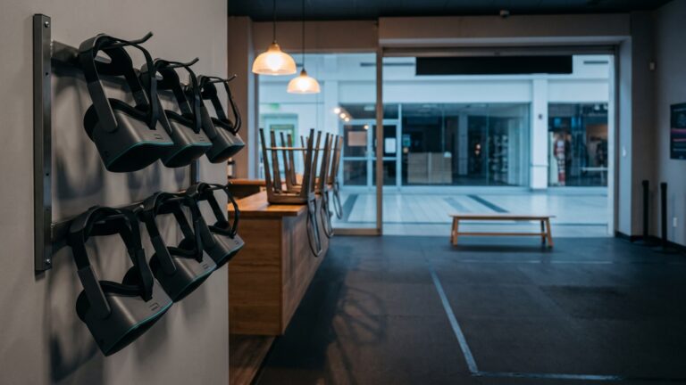 An empty VR venue after hours, with headsets on a wall rack and stools stacked on the counter. AI-generated image.